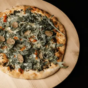 Pizza à la crème de truffe avec tomates cerises, ail, ruccola et copeaux de parmesan